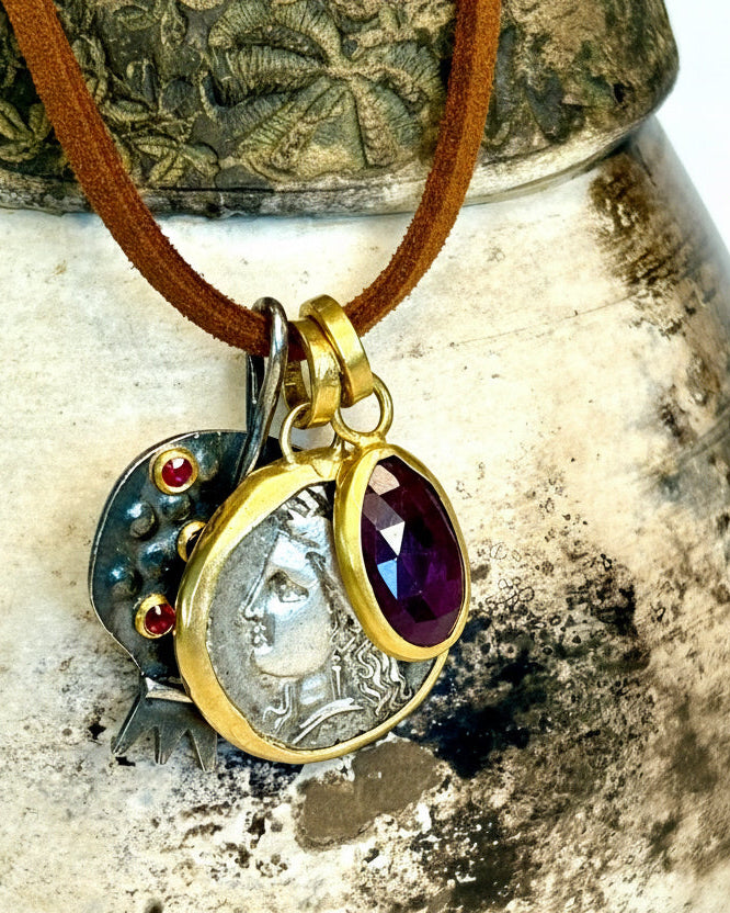 Necklace with a pendant featuring a coin and gemstones on a textured surface